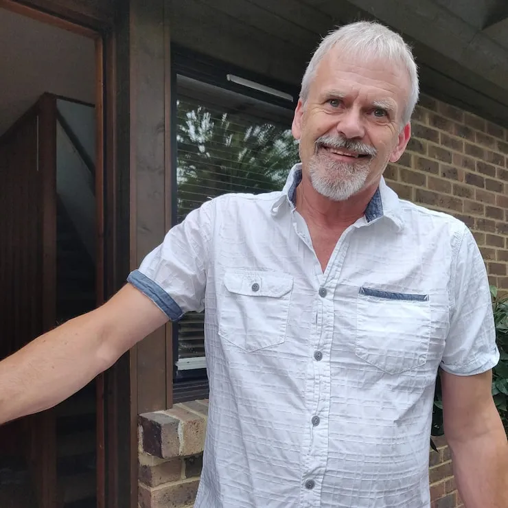 homem na porta de casa fazendo uma foto sorridente