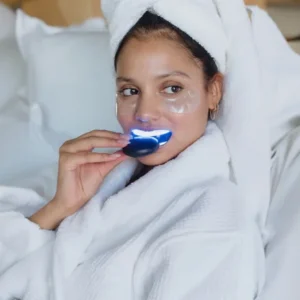 Woman using a teeth whitener as part of an at-home beauty routine.